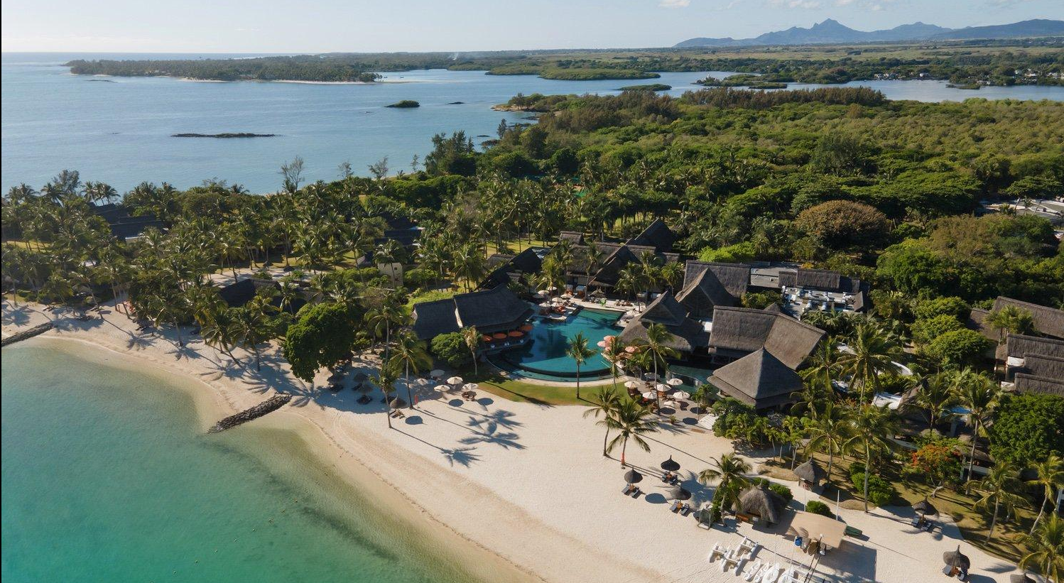 Luftaufnahme eines tropischen Resorts an der Küste Mauritus mit weißem Strand, türkisfarbenem Wasser und Poolanlage